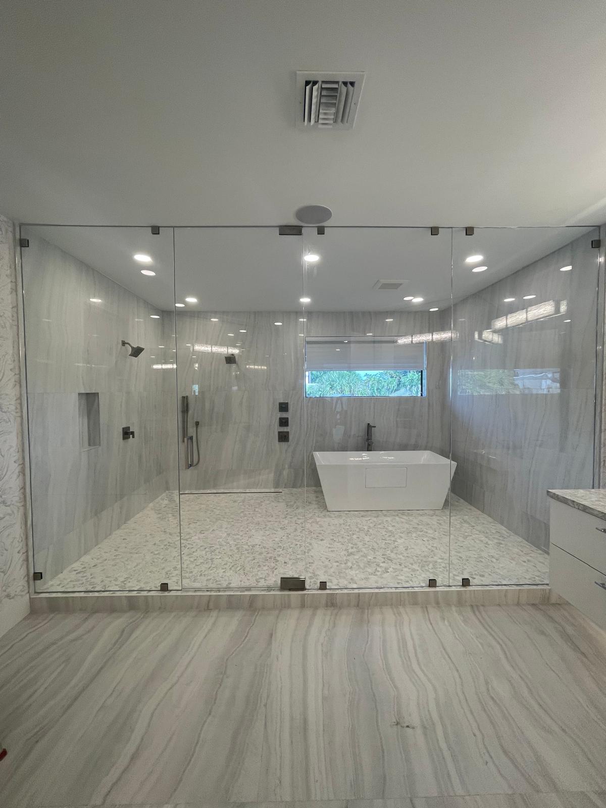 Modern bathroom with large glass shower, white bathtub, and gray marble walls and floor.
